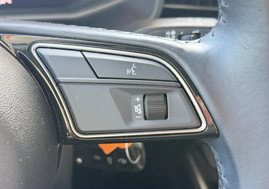 Gros plan sur les boutons de commande audio au volant en cuir noir de l'Audi A1 Sportback bleu firmament, version 2020.