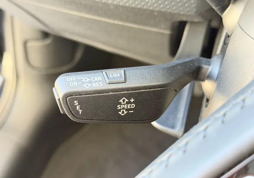 Le levier de régulateur de vitesse noir vu en gros plan côté gauche du volant dans l’habitacle d’une Audi A1 Sportback 2020 bleu firmament.