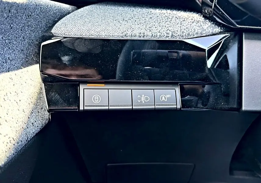 Gros plan sur les commandes de réglage des feux et du démarrage automatique dans l'habitacle d'une Renault Clio VI gris schiste.