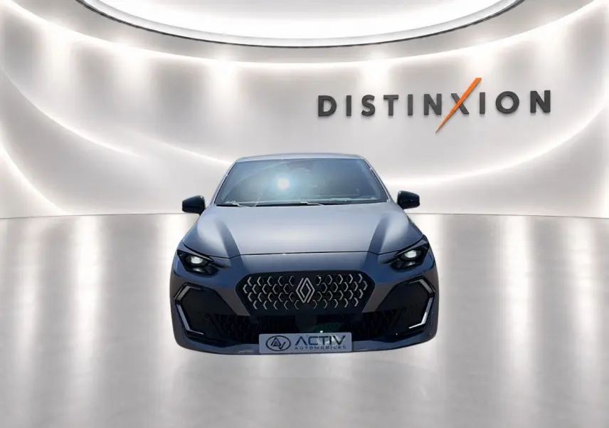 Renault Clio VI gris schiste vue de face dans un showroom avec éclairage moderne et logo Distinxion en arrière-plan.