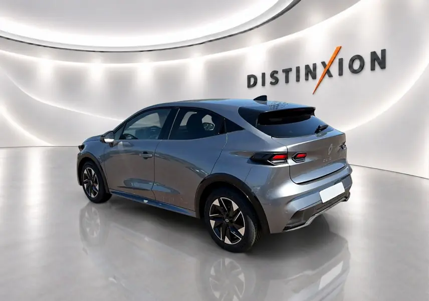 Renault Clio VI gris schiste vue 3/4 arrière droit dans un showroom lumineux avec jantes alu noires.