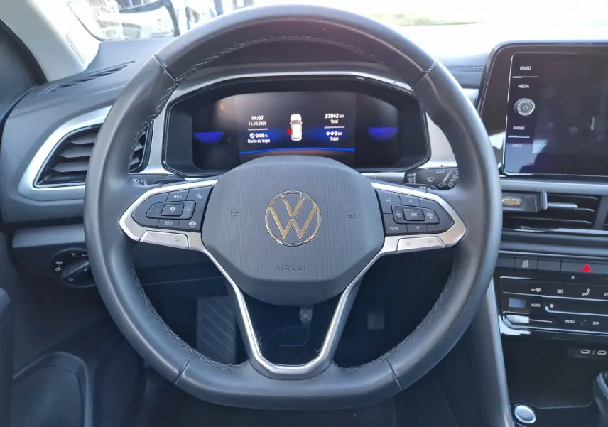 Vue intérieure centrée sur le volant noir de la Volkswagen T-Roc 2023 avec tableau de bord digital et écran tactile.