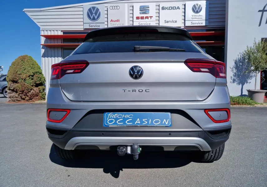 Vue arrière d'un Volkswagen T-Roc gris pyrite 2023 avec attelage et feux arrière LED visibles.