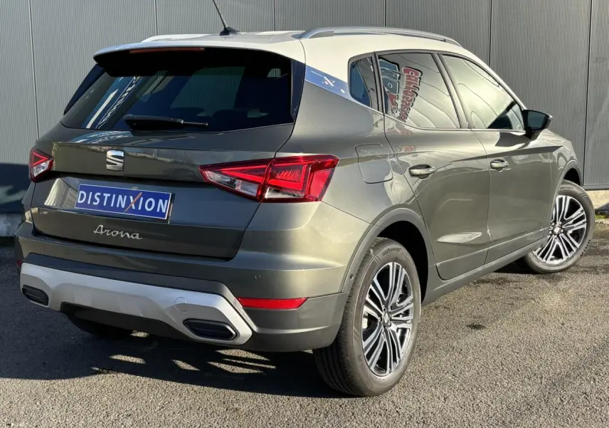 Vue 3/4 arrière droit d'une SEAT Arona gris Cliff avec toit blanc et jantes alliage 17 pouces, signature Arona visible.