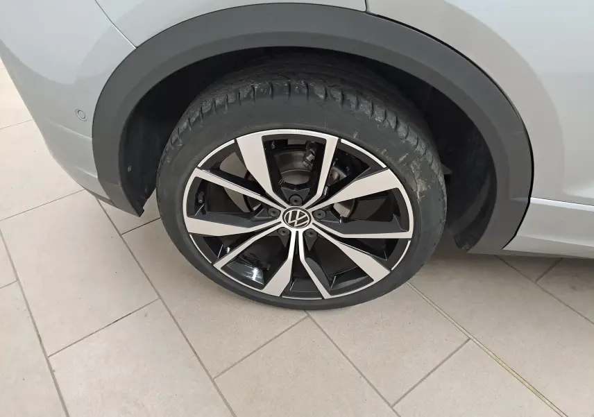 Gros plan sur la roue avant gauche du Volkswagen T-Roc gris Pyrite, avec jante alliage noir et argent 19 pouces.