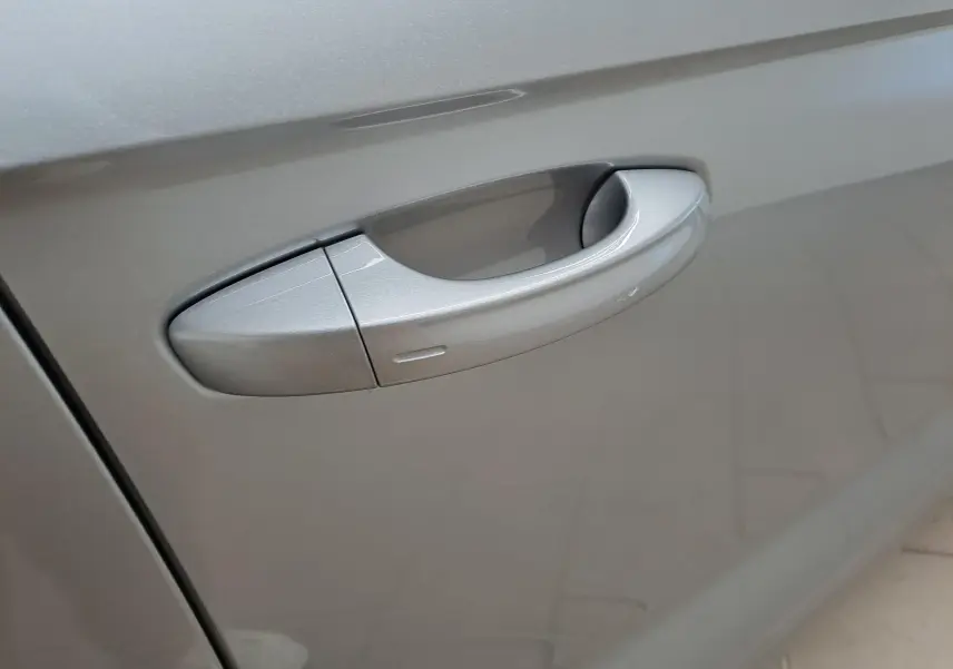 Poignée de porte côté gauche du Volkswagen T-Roc gris pyrite, mettant en valeur la finition lisse et métallisée.