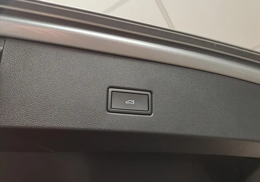 Bouton d'ouverture électrique du coffre sur la partie intérieure du hayon du Volkswagen T-Roc gris Pyrite.