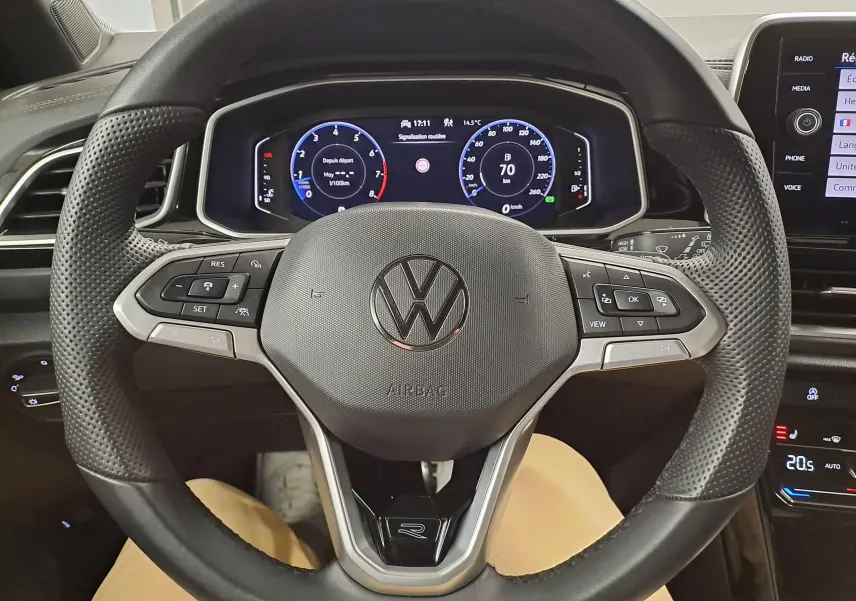 Vue intérieure centrée sur le volant multifonction perforé du Volkswagen T-Roc 1.5 TSI R-Line avec tableau de bord numérique.