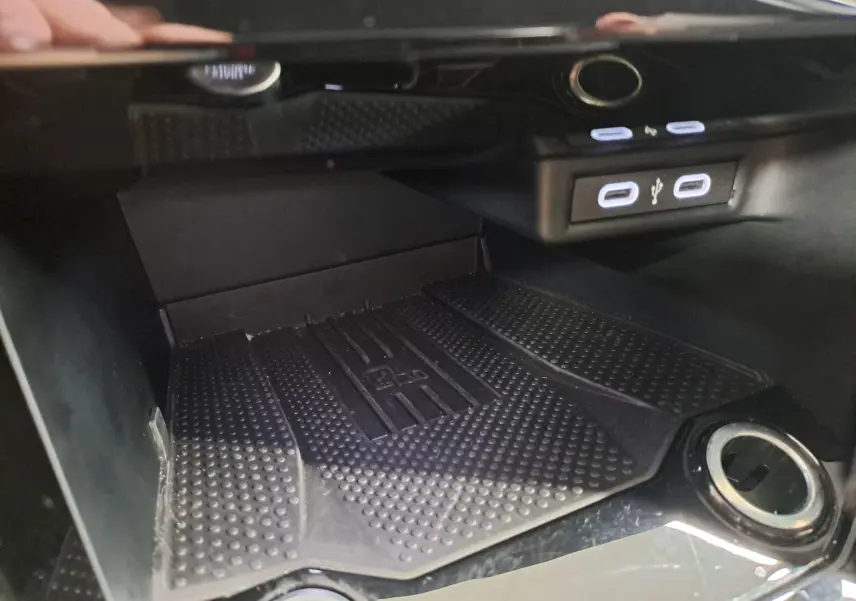 Gros plan intérieur sur la console centrale du Volkswagen T-Roc 2025, montrant la zone de recharge et ports USB éclairés.