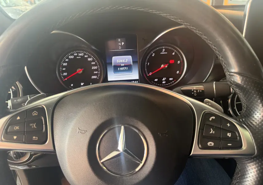 Vue intérieure centrée sur le volant noir d'un Mercedes GLC Coupé 2018, avec tableau de bord et compteurs visibles.