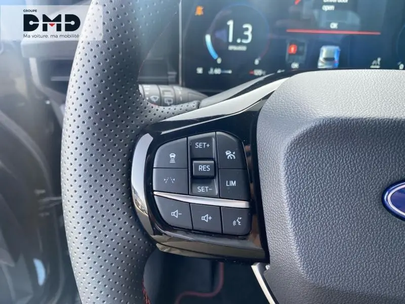 Gros plan sur les commandes multifonctions au volant côté gauche de la Ford Puma noir Agate Métallisée, avec tableau de bord numérique en arrière-plan.