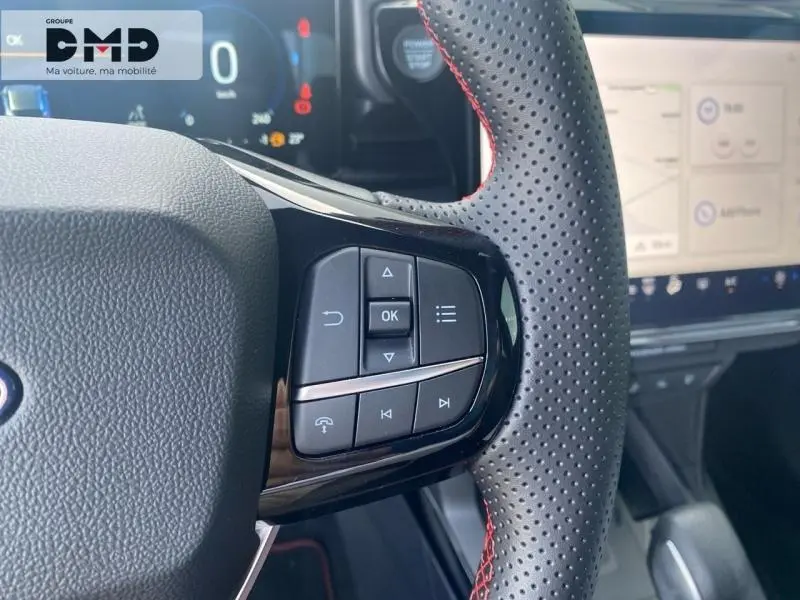 Gros plan sur les commandes du volant perforé noir avec surpiqûres rouges du Ford Puma noir Agate Métallisée, intérieur moderne.