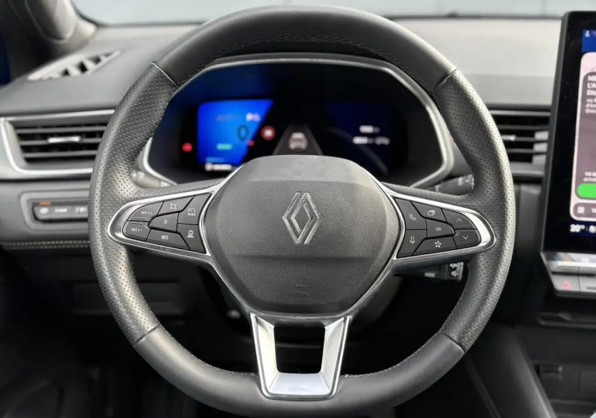 Vue frontale du volant noir perforé de la Renault SYMBIOZ E-Tech 2025 avec commandes intégrées et tableau de bord numérique bleu.