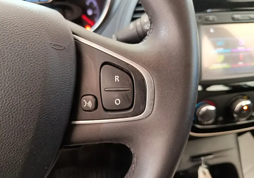 Gros plan sur le volant noir multifonctions du Renault Captur 2018 avec tableau de bord et écran tactile flous en arrière-plan.