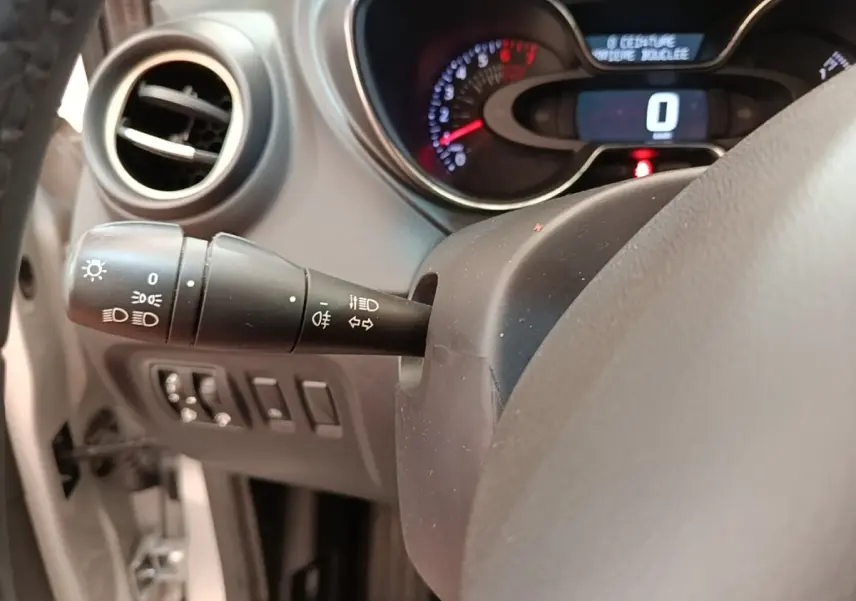 Vue rapprochée du tableau de bord et du commodo gauche du Renault Captur gris clair, affichage digital et commandes lumineuses visibles.