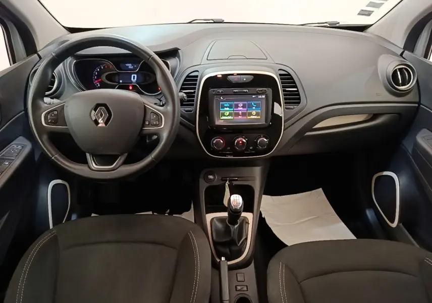 Vue intérieure frontale du tableau de bord du Renault Captur gris clair avec volant multifonctions et écran tactile central.