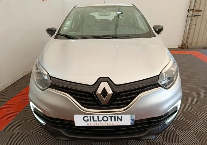 Vue frontale d'un Renault Captur gris clair 2018 avec feux de jour LED allumés dans un garage.
