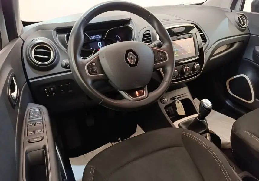Vue intérieure du poste de conduite Renault Captur gris clair 2018, volant multifonction et tableau de bord avec écran tactile.