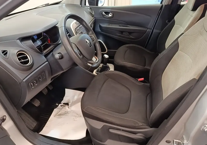 Vue intérieure côté conducteur du Renault Captur gris clair 2018, montrant sièges noirs et tableau de bord avec volant multifonctions.