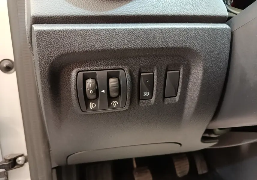 Gros plan sur les commandes de réglage des phares et autres boutons côté gauche du tableau de bord d’un Renault Captur gris clair 2018.