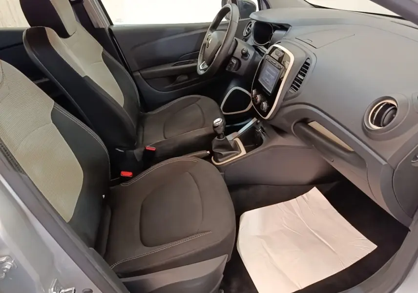 Vue intérieure côté conducteur de la Renault Captur gris clair 2018, montrant les sièges et le tableau de bord avec écran tactile.