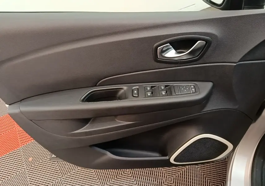 Vue rapprochée de la porte avant gauche du Renault Captur gris clair, avec commandes électriques et poignée argentée.