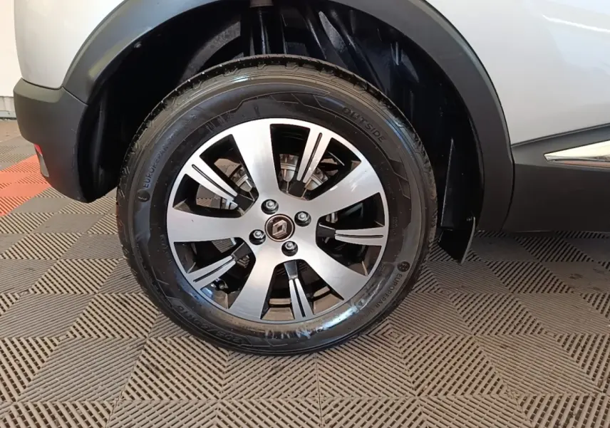 Gros plan sur la roue avant gauche d’un Renault Captur gris clair, avec jante alliage à cinq branches doubles.