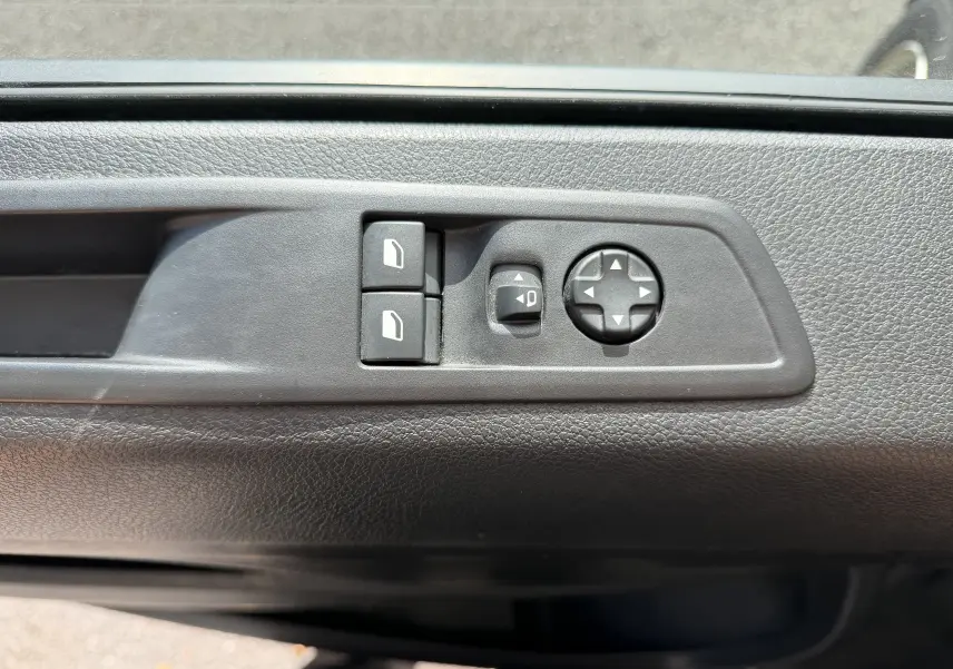 Gros plan sur les commandes de réglage des vitres et des rétroviseurs sur la porte intérieure noire d'un Fiat Scudo Fourgon blanc.