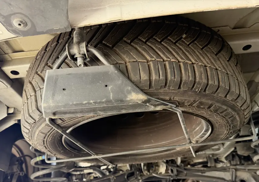 Gros plan sous le FIAT Scudo Fourgon blanc 2025 montrant la roue de secours fixée sous le châssis.