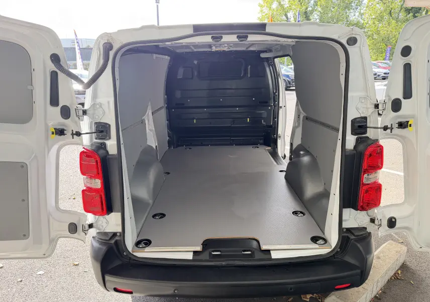 Vue arrière du fourgon blanc FIAT Scudo XL 180 avec portes ouvertes, montrant l’espace de chargement vide et aménagé.