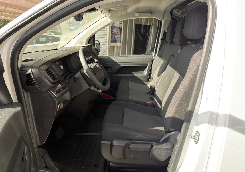 Vue intérieure côté conducteur du Fiat Scudo Fourgon blanc 2025, montrant la banquette modulable et le tableau de bord noir.