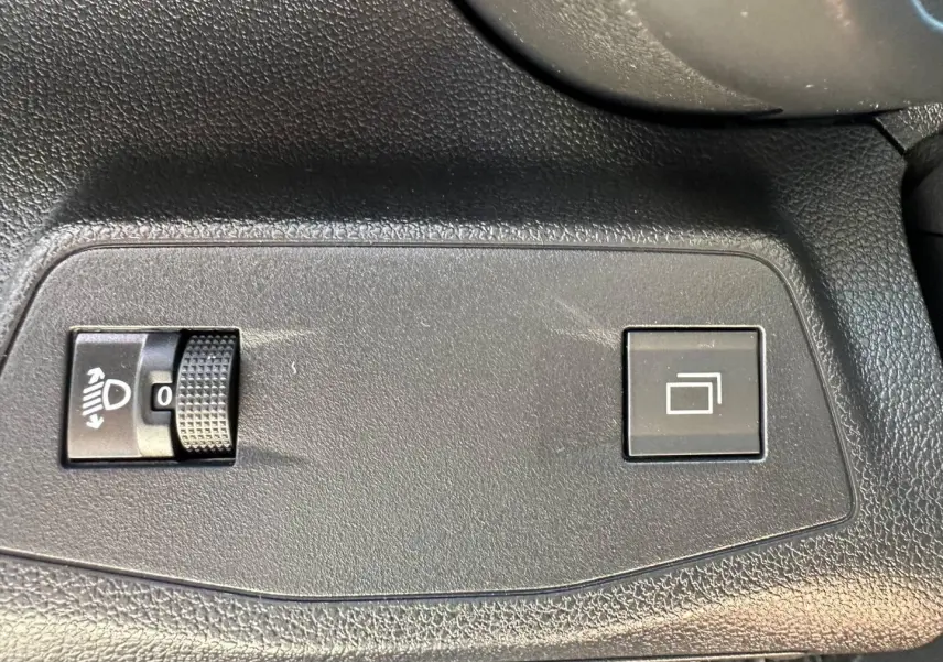 Détail intérieur montrant les commandes de réglage des phares et de l'affichage sur plastique noir texturé du Citroën Berlingo Kiama Blue.