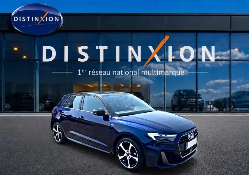 Audi A1 Sportback bleu foncé/noir en 3/4 avant, avec jantes alu et toit noir devant showroom Distinxion.