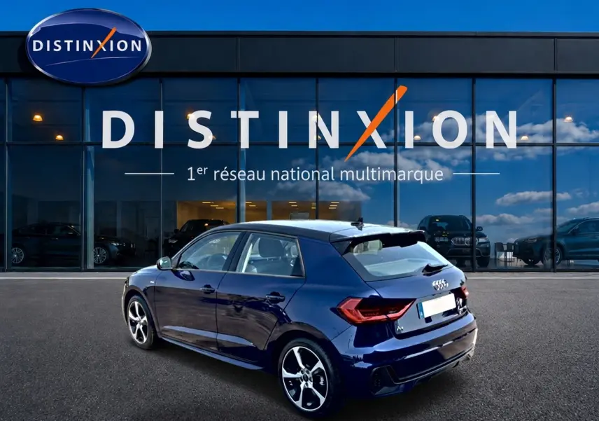 Audi A1 Sportback bleu foncé vue 3/4 arrière droit, avec jantes alu et becquet arrière distinctifs.