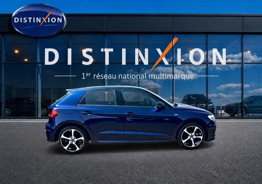 Audi A1 Sportback bleu foncé vue de profil côté gauche, avec jantes alliage et toit noir devant vitrine Distinxion.