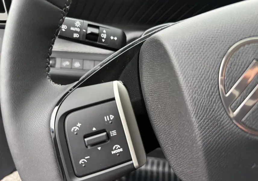 Gros plan sur les commandes au volant côté gauche du Citroën C3 hybride gris Mercury avec volant en cuir noir.