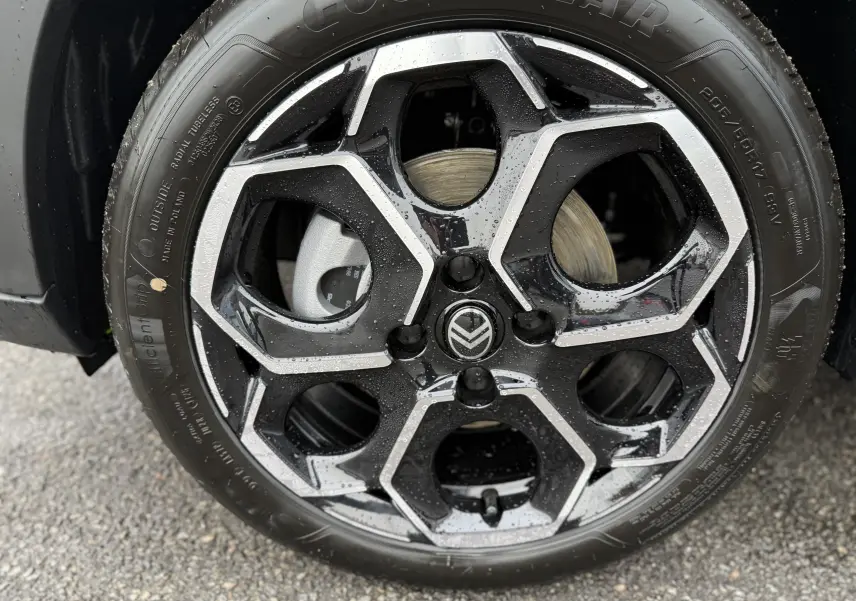 Gros plan sur la jante noire et argentée de la Citroën C3 hybride 2026, avec logo Citroën au centre et traces d'eau.