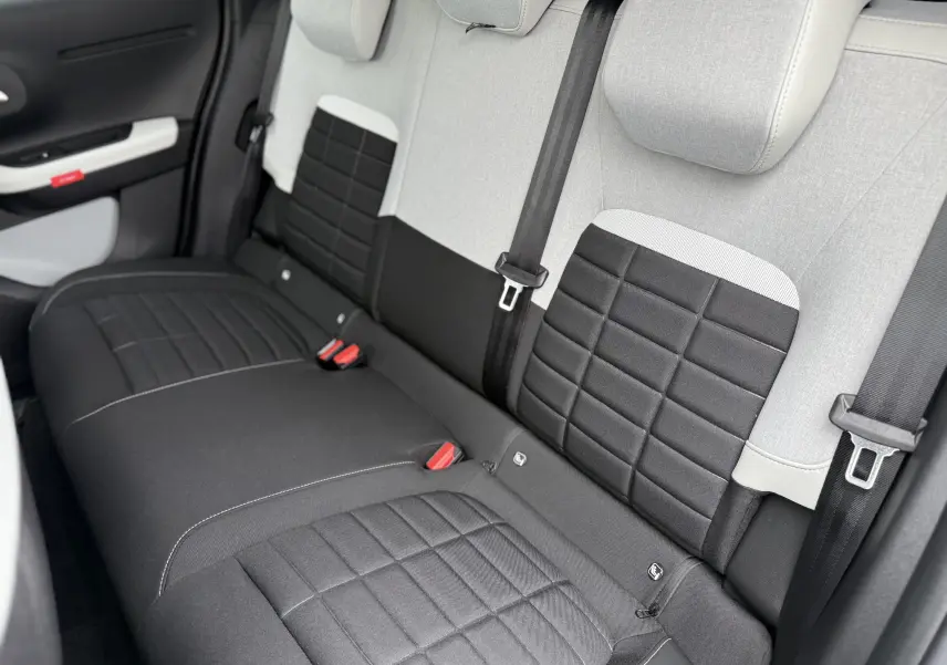 Vue intérieure arrière des sièges arrière gris clair et noir de la Citroën C3 hybride 2026 avec ceintures de sécurité visibles.