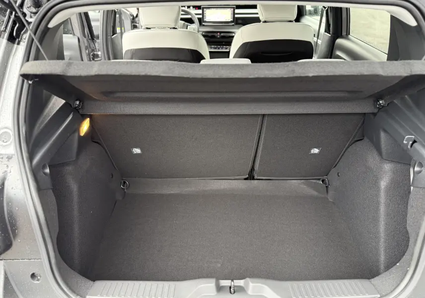 Coffre ouvert vu de l’arrière d’une Citroën C3 hybride gris Mercury avec intérieur clair et tablette de séparation.
