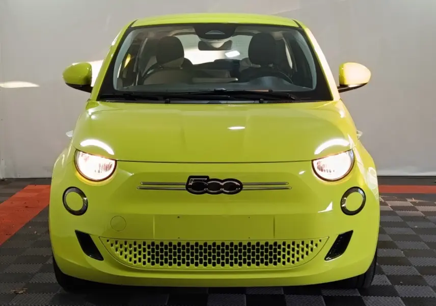 Vue frontale d'une FIAT 500 BEV 24KWH jaune vif avec phares allumés et logo 500 centré sur la calandre.