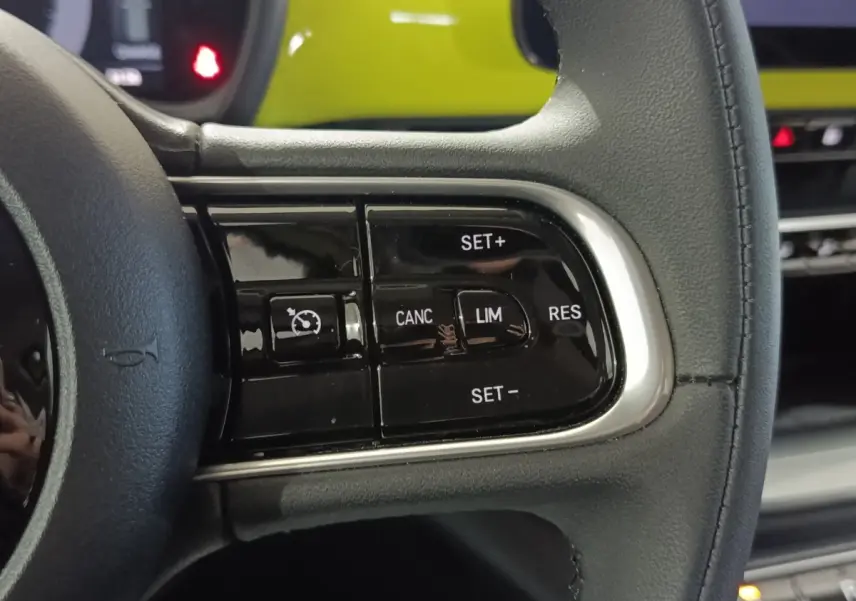 Gros plan sur le volant en cuir synthétique noir du Fiat 500 BEV 24KWH 2024, avec commandes multifonctions visibles.