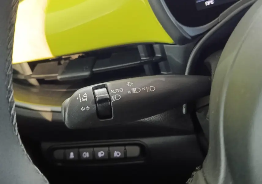 Gros plan sur la manette de commande des feux et clignotants, avec partie intérieure jaune vif visible du Fiat 500 électrique 2024.