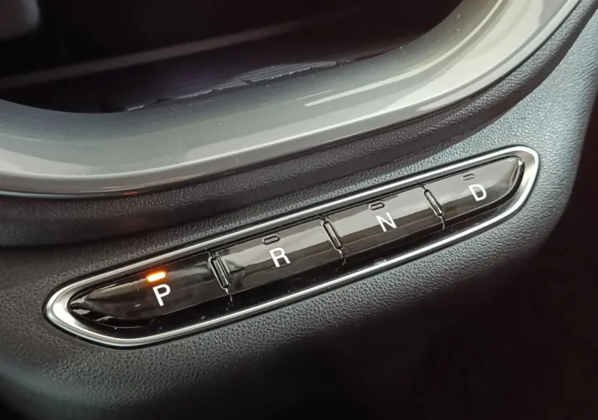 Gros plan sur les boutons de la boîte automatique noire avec indication orange sur la position "P" dans une Fiat 500 BEV jaune.
