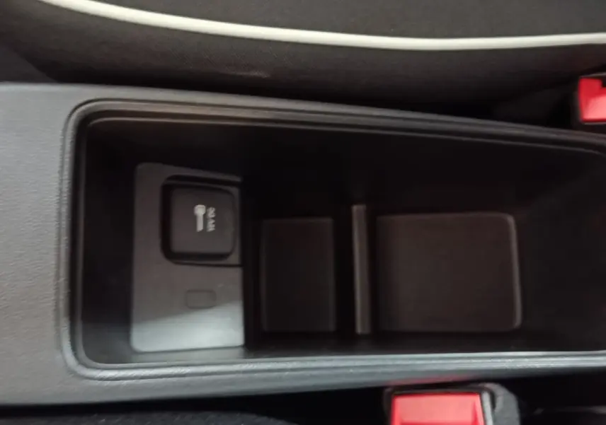 Vue rapprochée de la console centrale noire du Fiat 500 BEV 24KWH avec prise 12V et bouton de verrouillage.
