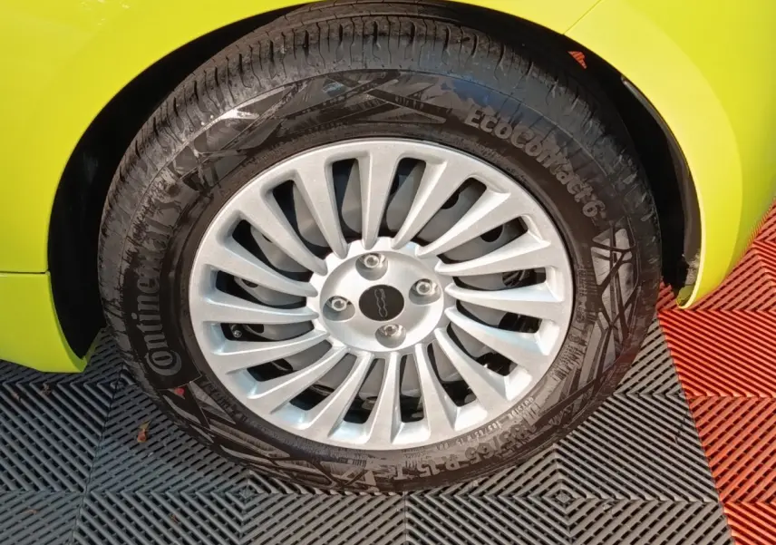 Gros plan sur la roue avant droite d'une FIAT 500 BEV 24KWH jaune avec jante argentée à rayons fins.