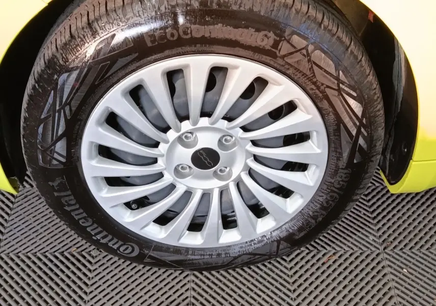 Gros plan sur la roue avant droite d'une FIAT 500 BEV 24KWH jaune avec jante argentée multibranches.
