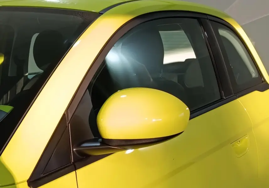 Gros plan sur le rétroviseur côté gauche d'une FIAT 500 BEV 24KWH jaune électrique, avec vitre arrière visible.