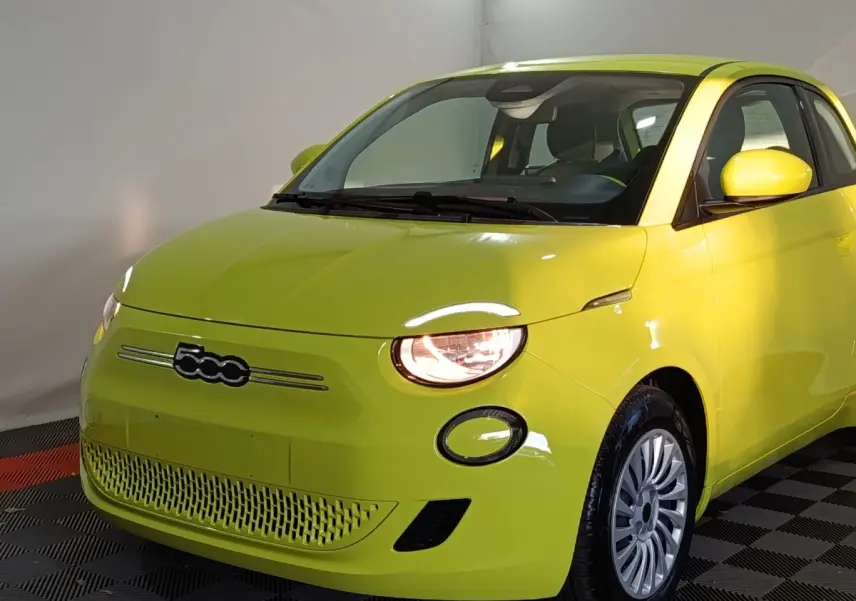 Vue 3/4 avant droite d'une FIAT 500 BEV 24KWH jaune électrique avec phares allumés et jantes argentées.