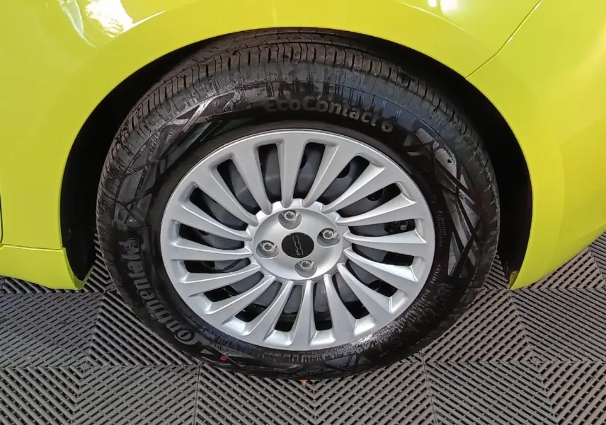 Gros plan sur la roue avant gauche d'une FIAT 500 BEV 24KWH jaune, avec jante argentée multi-branches.