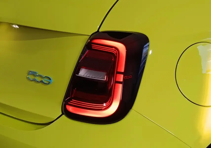 Gros plan sur le feu arrière droit rouge et le logo 500e bleu d'une FIAT 500 électrique jaune vif.